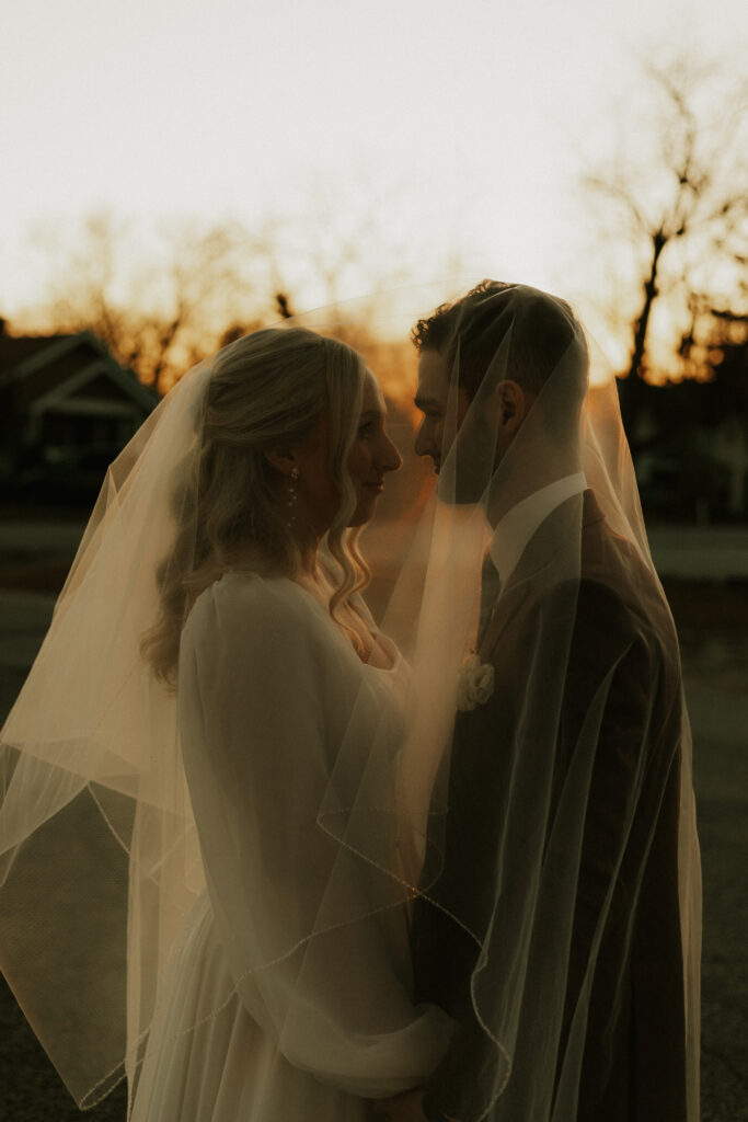 upscale bride and groom portraits outside of historical wedding venue during golden hour under veil photography