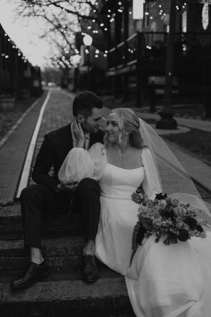 upscale bride and groom portraits outside of historical wedding venue during golden hour with sparkling lights and colorful wedding bouquets sitting on stairs