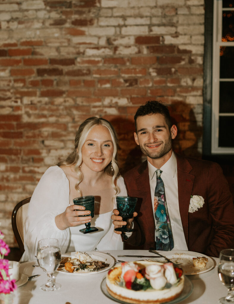 bride and groom at wedding reception with goblets and dinner in a historical brick wedding venue
