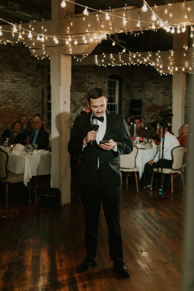 speeches at wedding reception by best man in historical wedding venue with sparkling lights