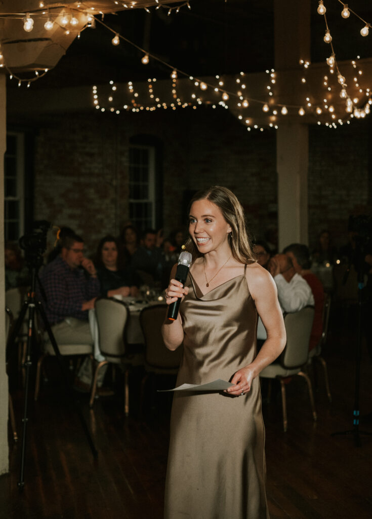 speeches at wedding reception by maid of honor in historical wedding venue with sparkling lights