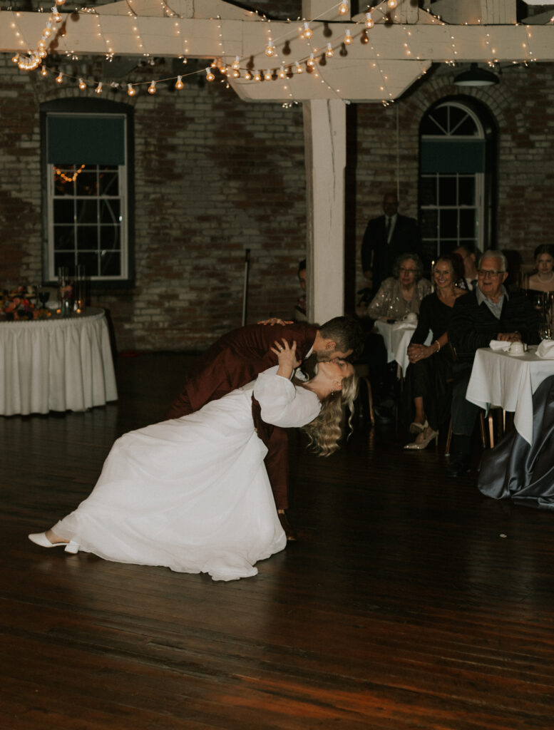 coordinated first dance of bride and groom at wedding reception with a dip and kiss
