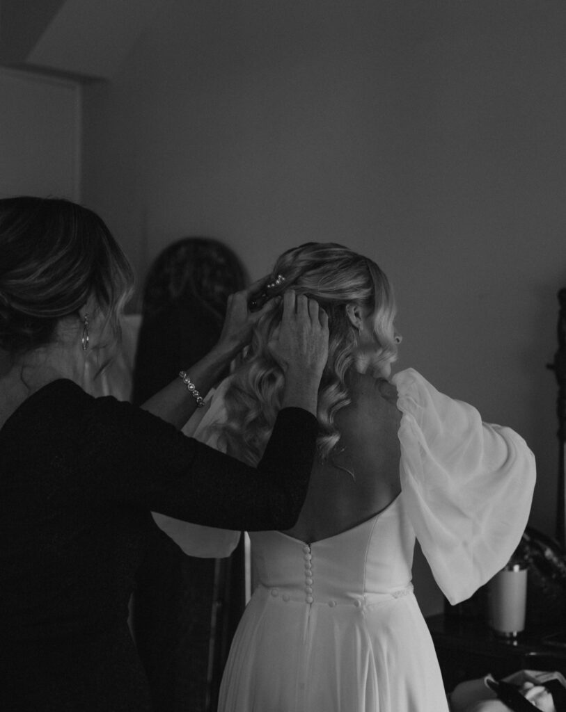 bride getting ready in bridal suite at Bread & Chocolate wedding venue, mom zipping up dress and fixing hair