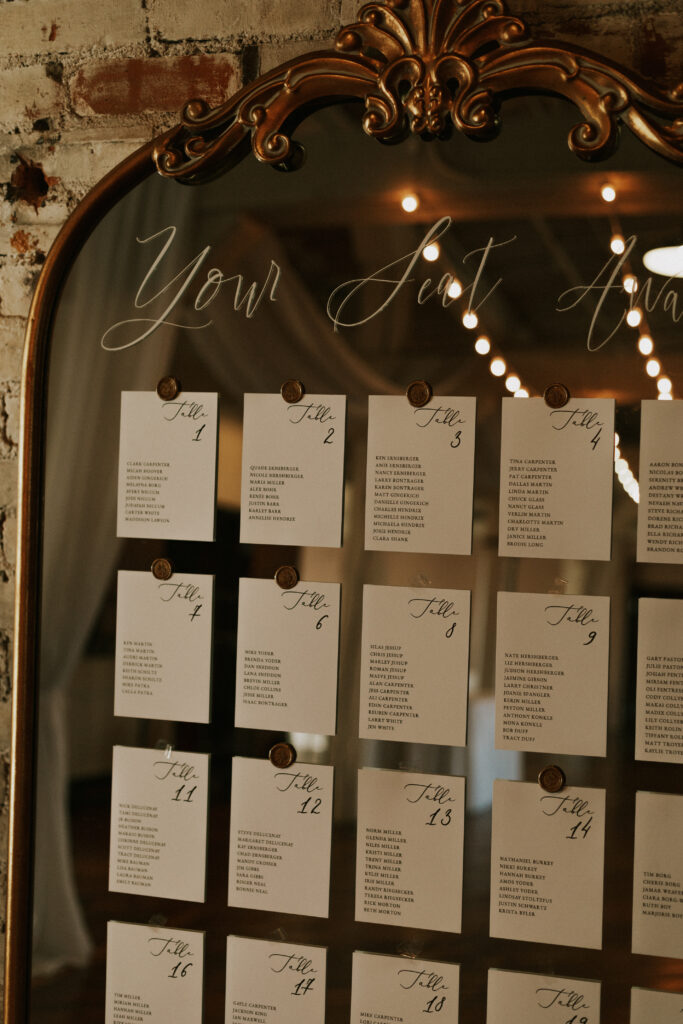 wedding seating chart on vintage gold mirror with handwritten calligraphy and wax seals