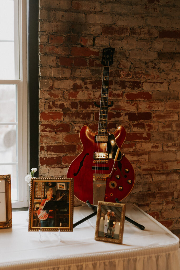 in memory of wedding table with a red electric guitar and framed pictures of relatives