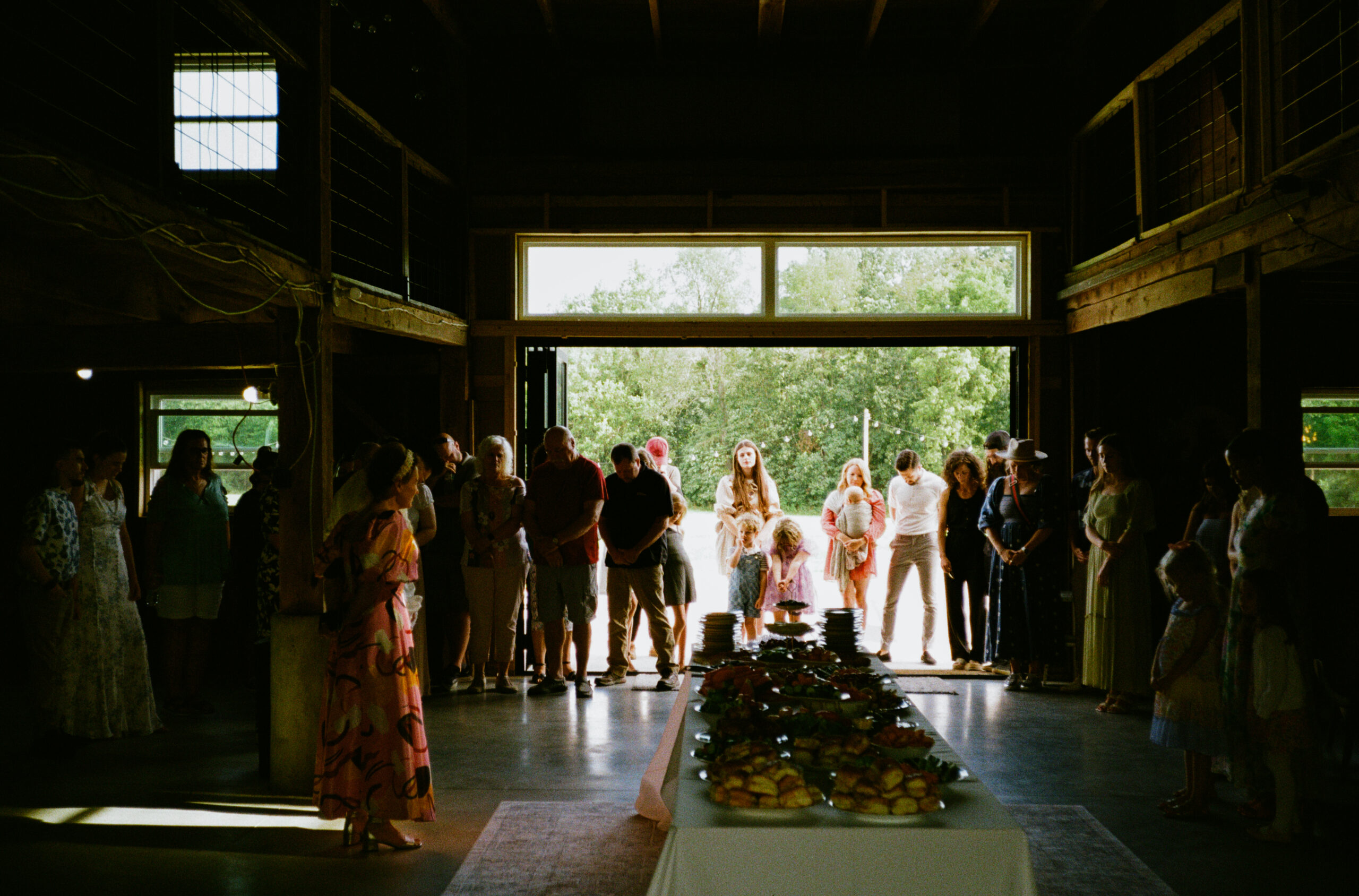 Guests praying with heads bowed at wedding reception in winona lake and warsaw indiana at an outdoor wedding.