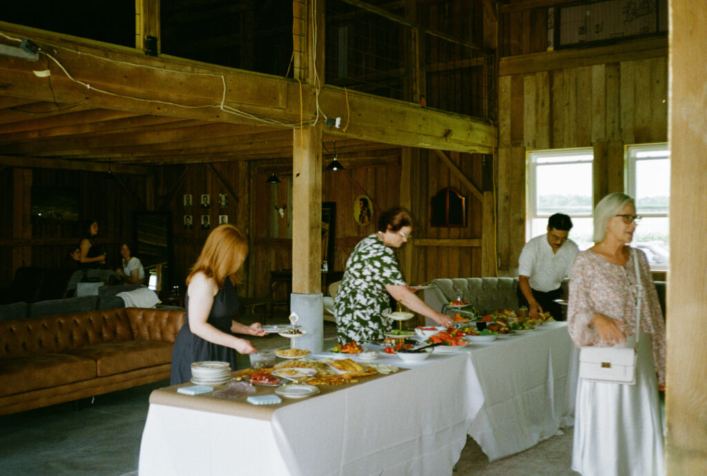 guests eating and grabbing charcuterie food at outdoor wedding reception in warsaw and winona lake indiana, on 35mm film photography.