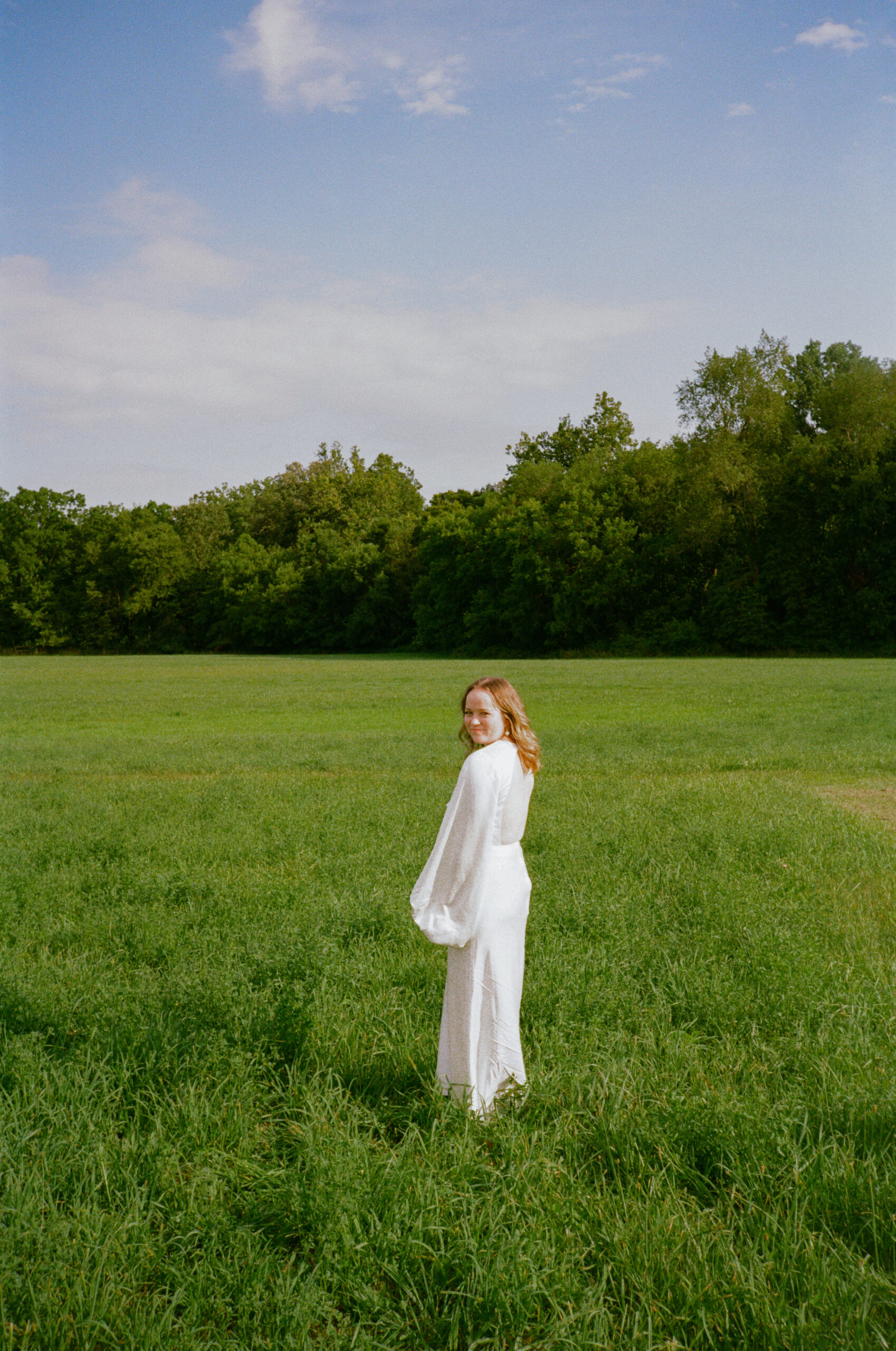 Bride portraits at wedding reception on 35mm film in meadow field, at golden hour, outside of outdoor wedding reception.