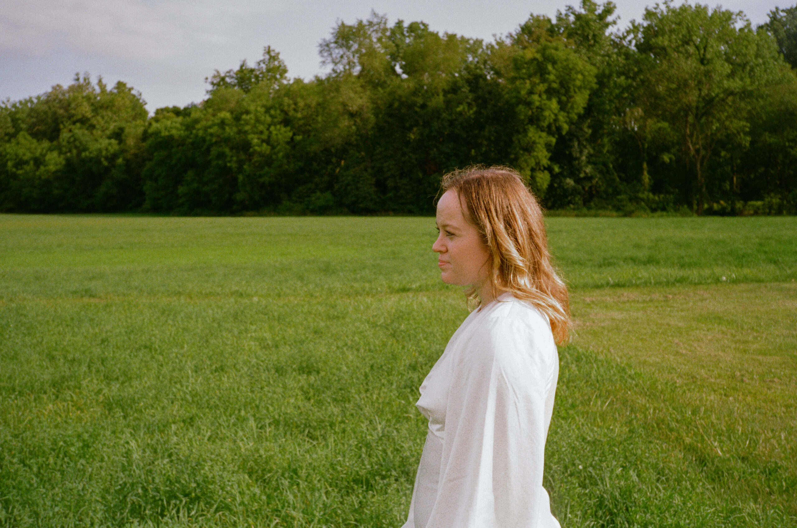 Bride portraits at wedding reception on 35mm film in meadow field, at golden hour, outside of outdoor wedding reception.