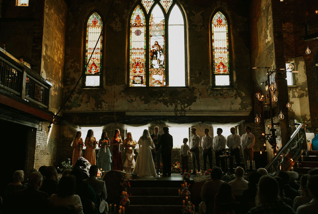 Bride and groom stand with wedding party at wedding ceremony stage at North Church Venue in Muncie, Indiana