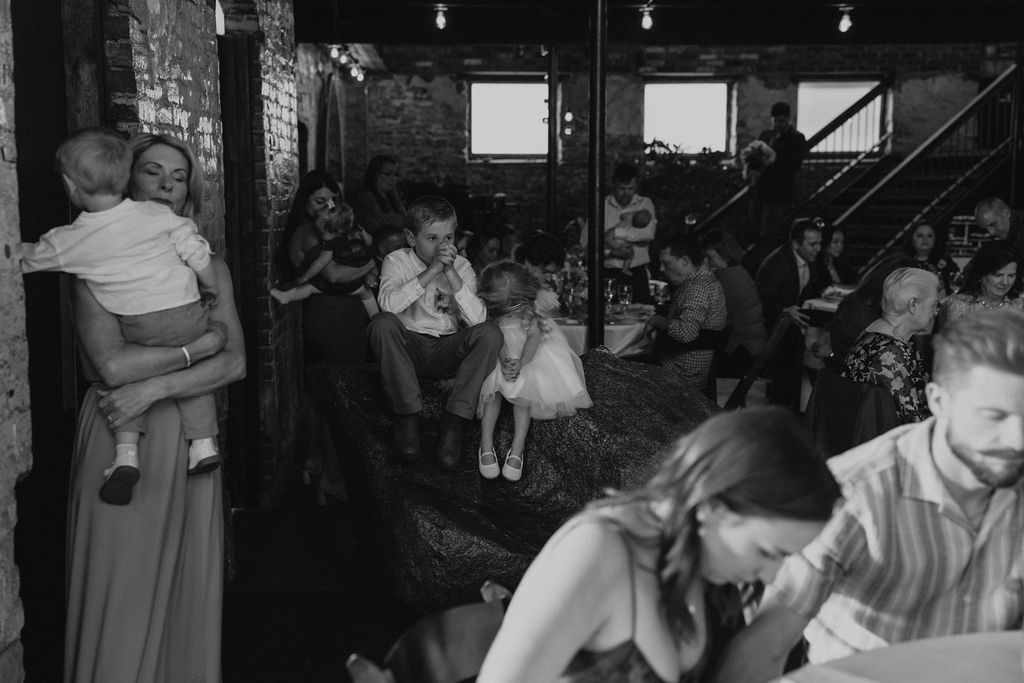 Flower girl and ring bearer at wedding reception sitting together during prayer at North Church Venue in Muncie, Indiana.