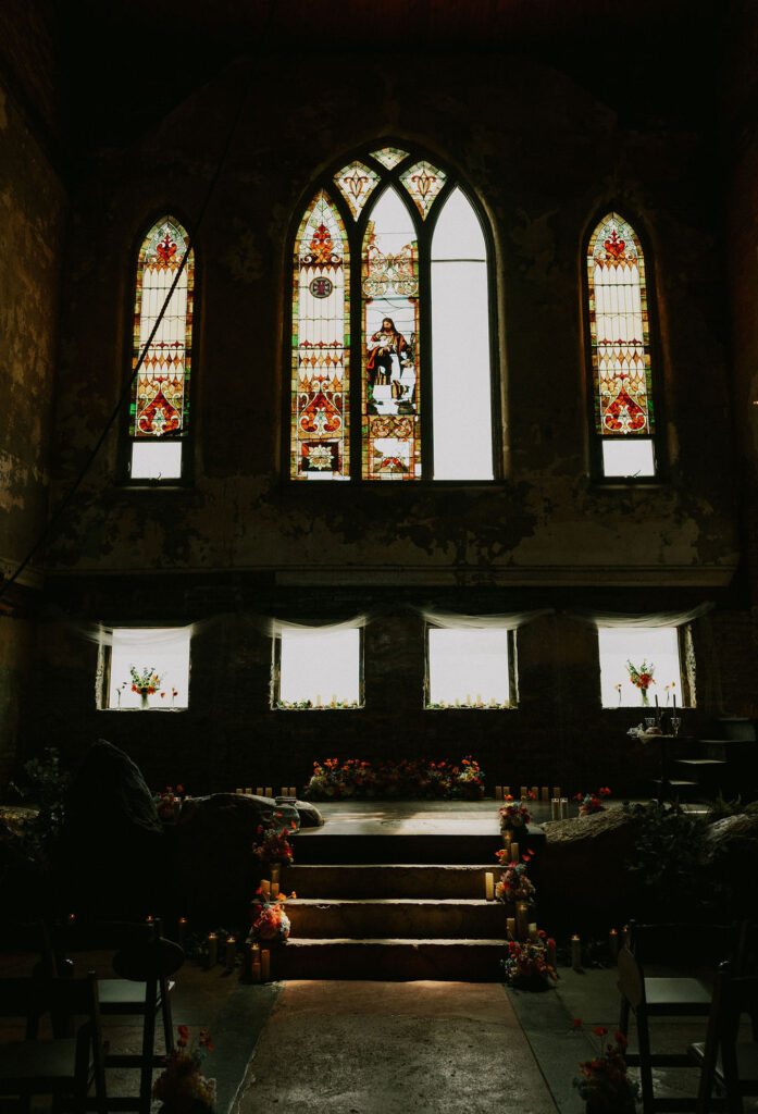 Eclectic wedding florals, colorful bouquets lining a historic stairway with stained glass windows in The North Church venue in Muncie, Indiana.