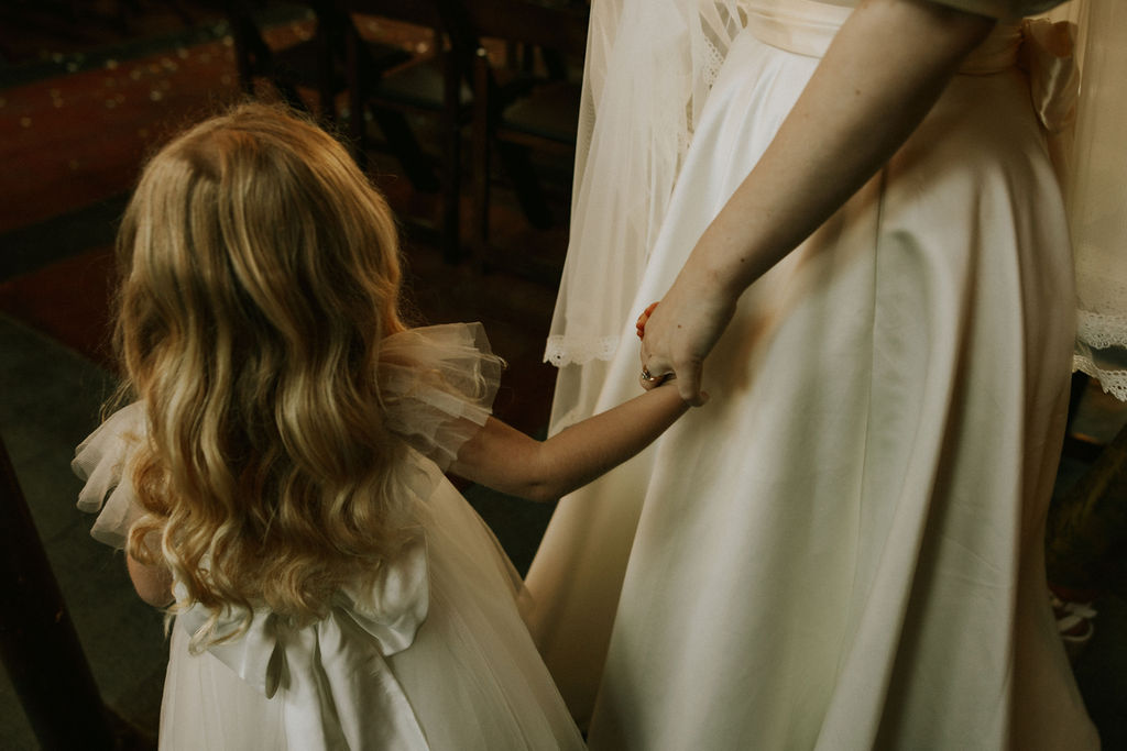 Groom talking to flower girl at wedding day in Muncie, Indiana at the North Church Wedding Venue.