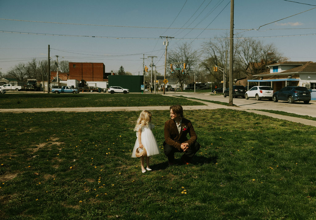 Groom talking to flower girl at wedding day in Muncie, Indiana at the North Church Wedding Venue.
