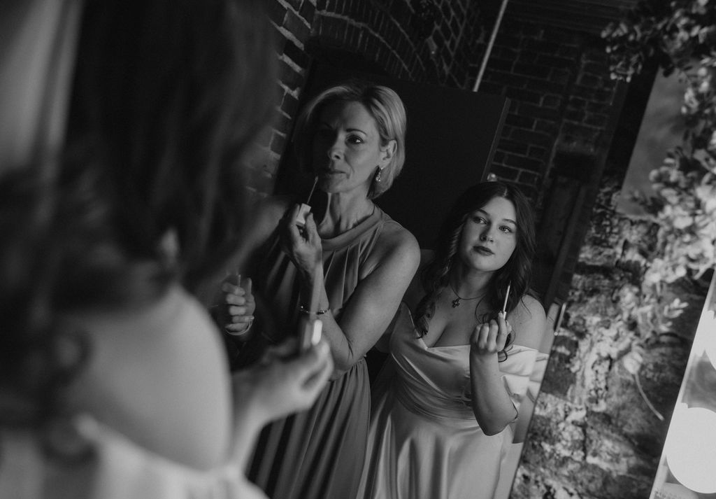 Bride and mom of bride getting ready and putting on lipstick on wedding day at The North Church Venue in Muncie, Indiana.