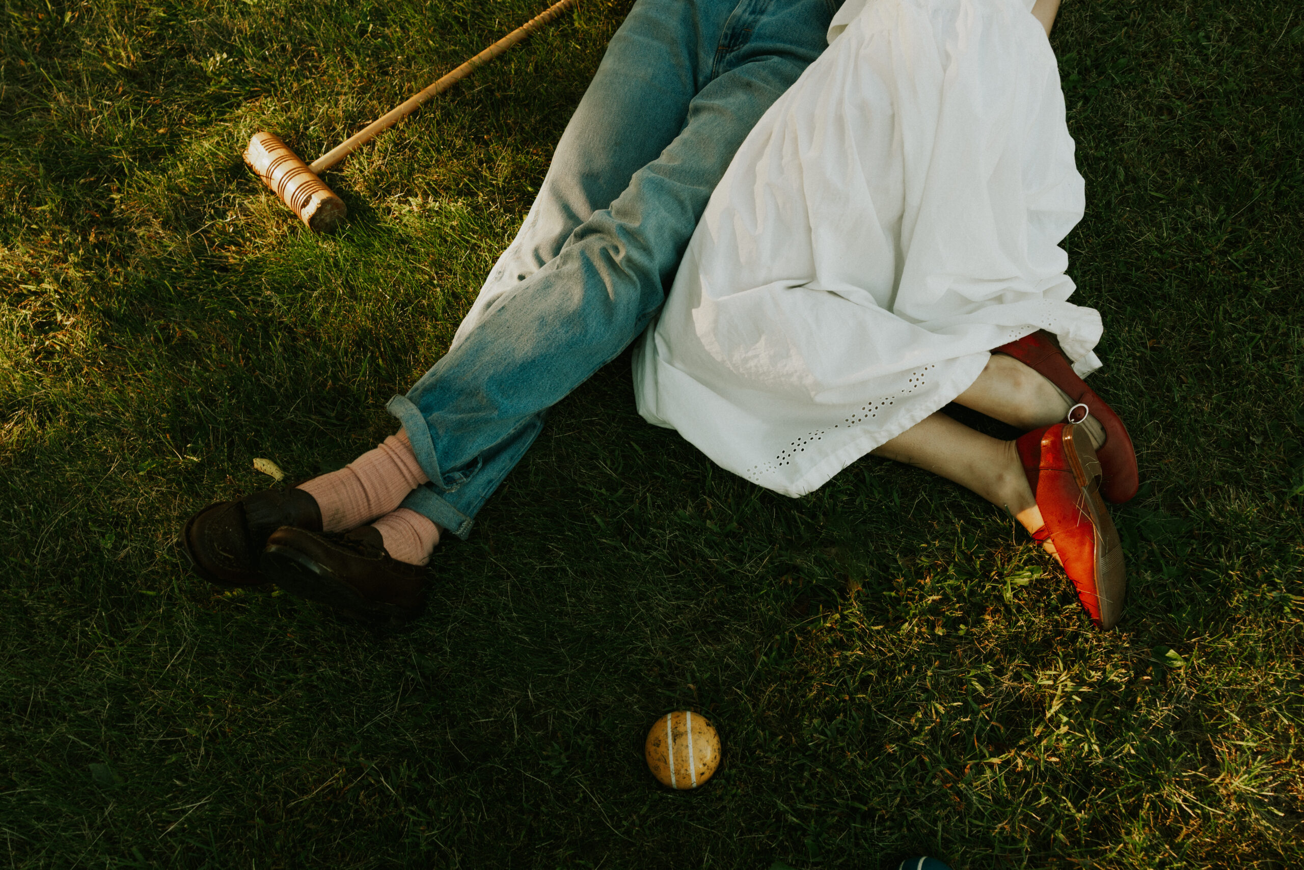 Engagement session couple laying on the ground, to show off details of their outfit and shoes.