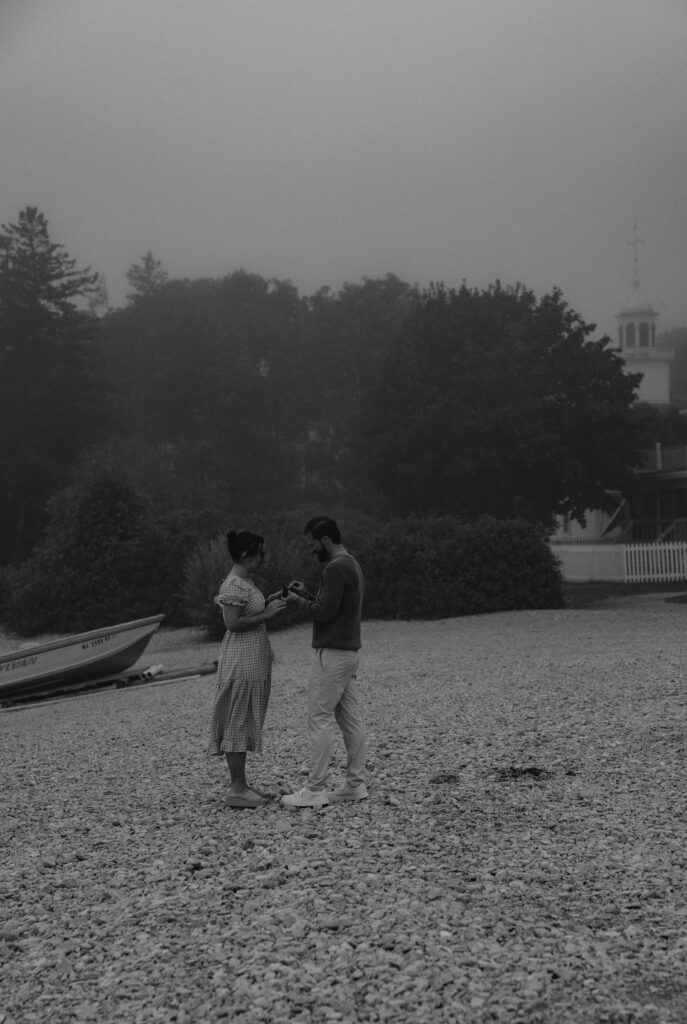 Couple getting engaged and kissing on Mackinac Island, Michigan on the beach.