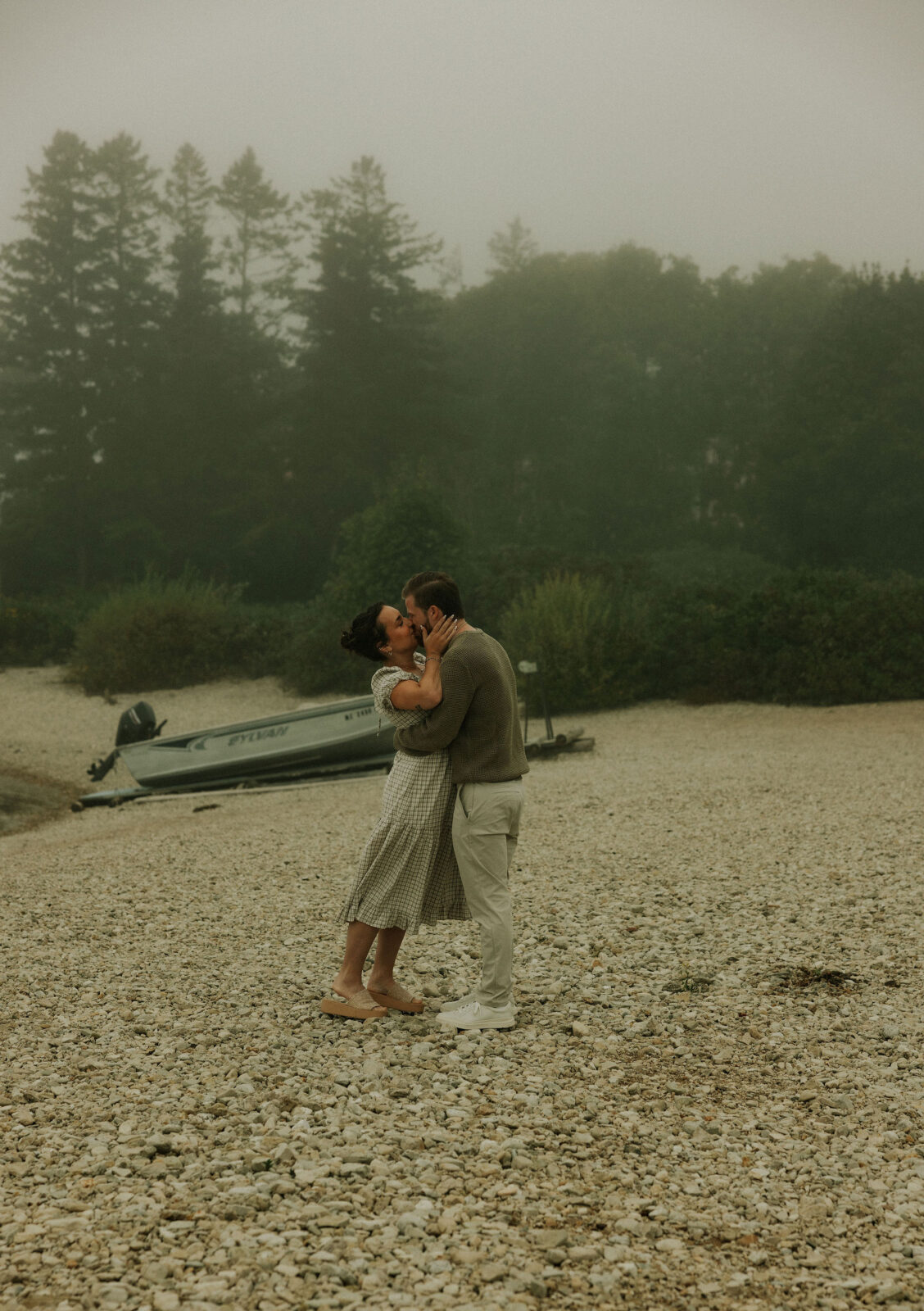 Couple getting engaged and kissing on Mackinac Island, Michigan on the beach.