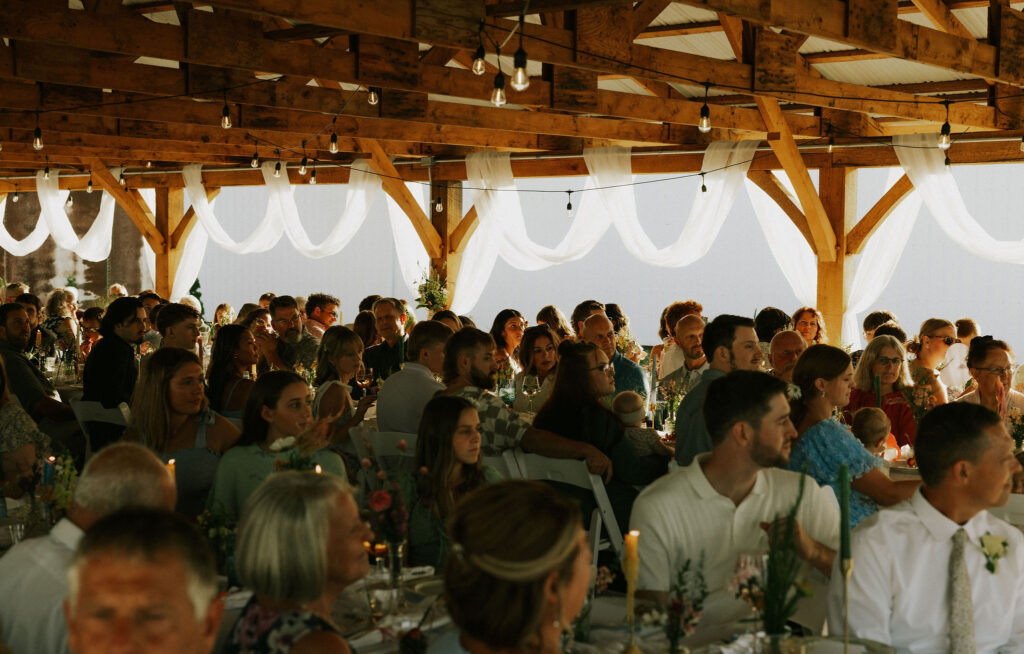 Wedding reception guests watching bride and groom, in the pavilion at Vintage Meadows.