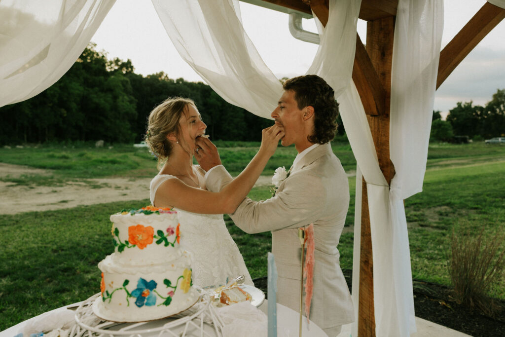 Bride and groom cut the cake, and feed each other a piece of cake.