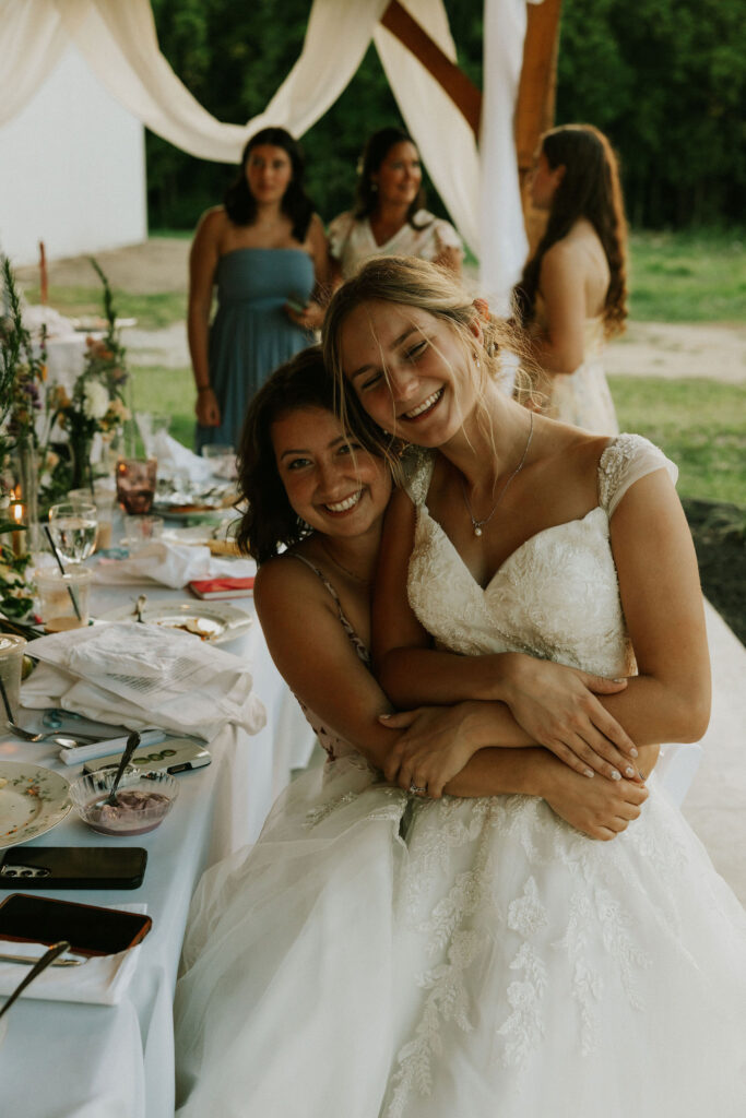 Bride and friend hugging at reception.