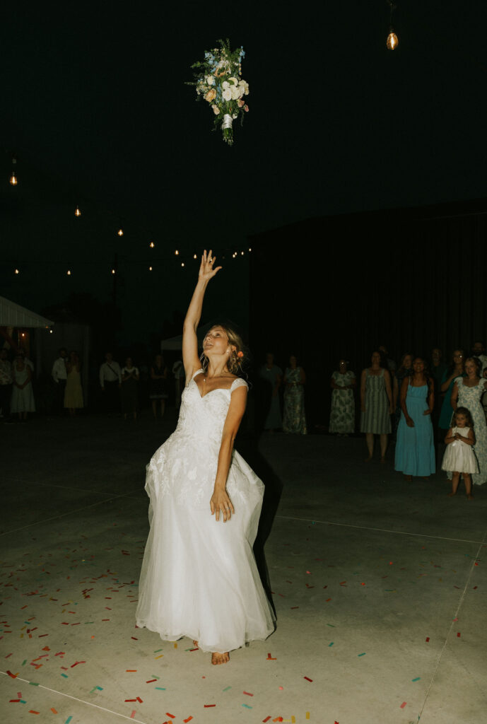 Bride throwing the bouquet to single women guests.
