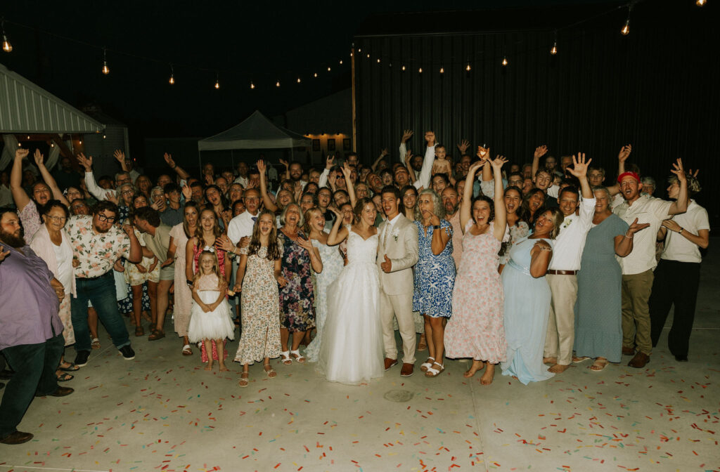 Group photo of all the guests with the bride and groom at Vintage Meadows in Goshen, IN.