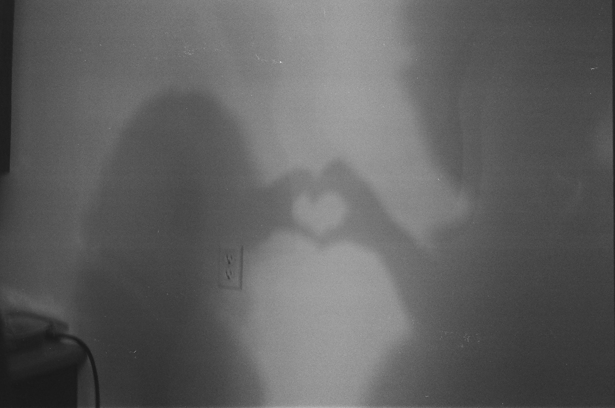 black and white film of a couple making a shadow heart with their hands together.