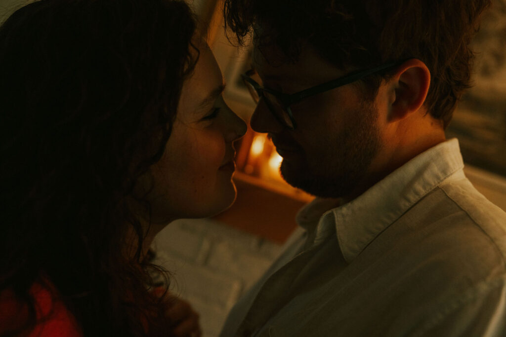 Couple cuddled in the living room of their home by candlelight.