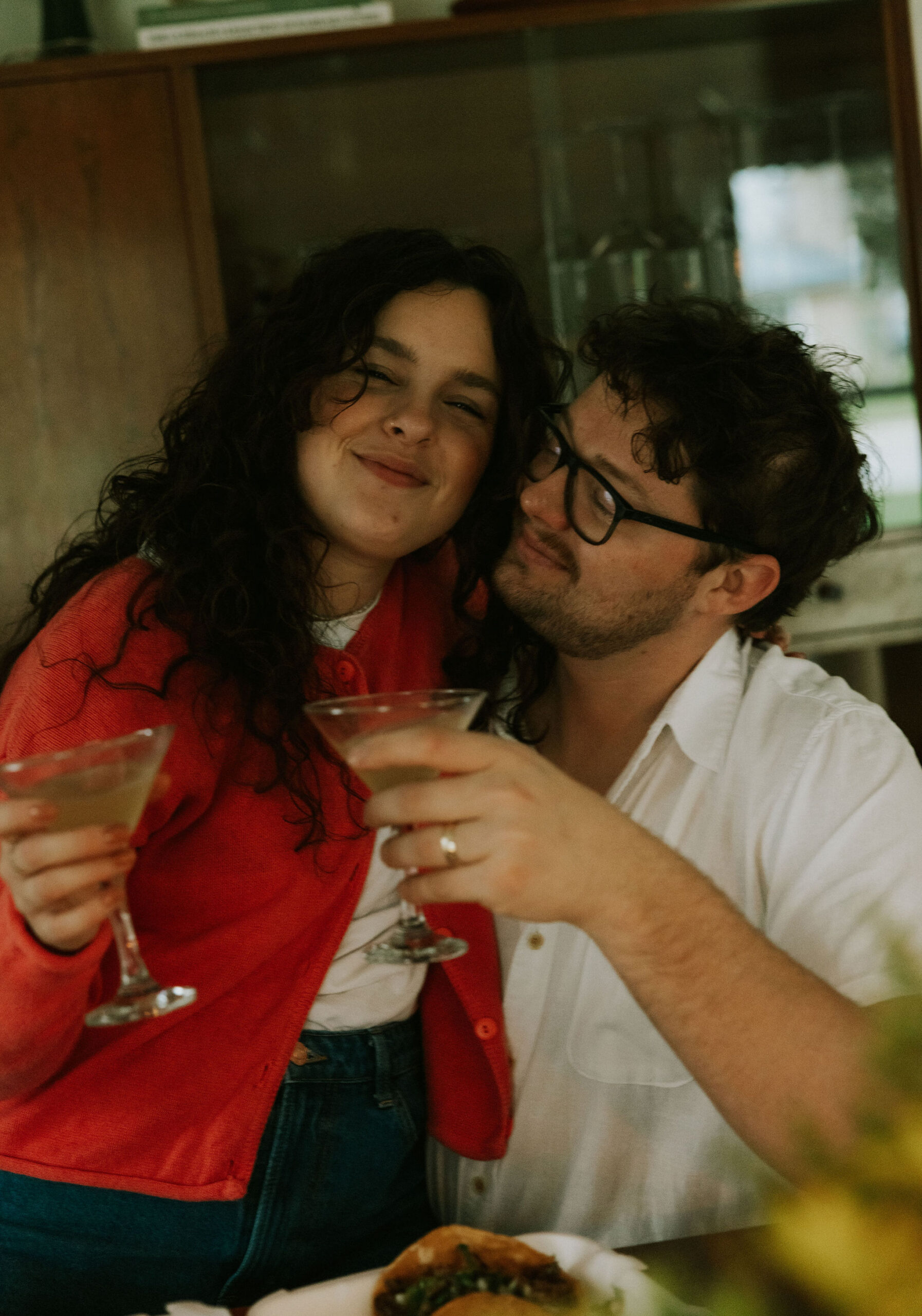 Couple cuddling at kitchen table drinking margaritas. 