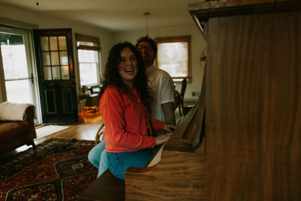 Couple cuddled in the living room at the piano of their home by candlelight. 