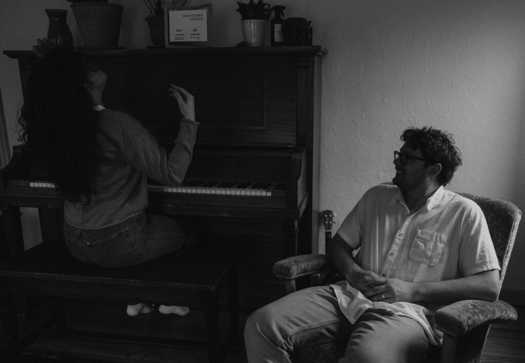 Couple cuddled in the living room at the piano of their home by candlelight.
