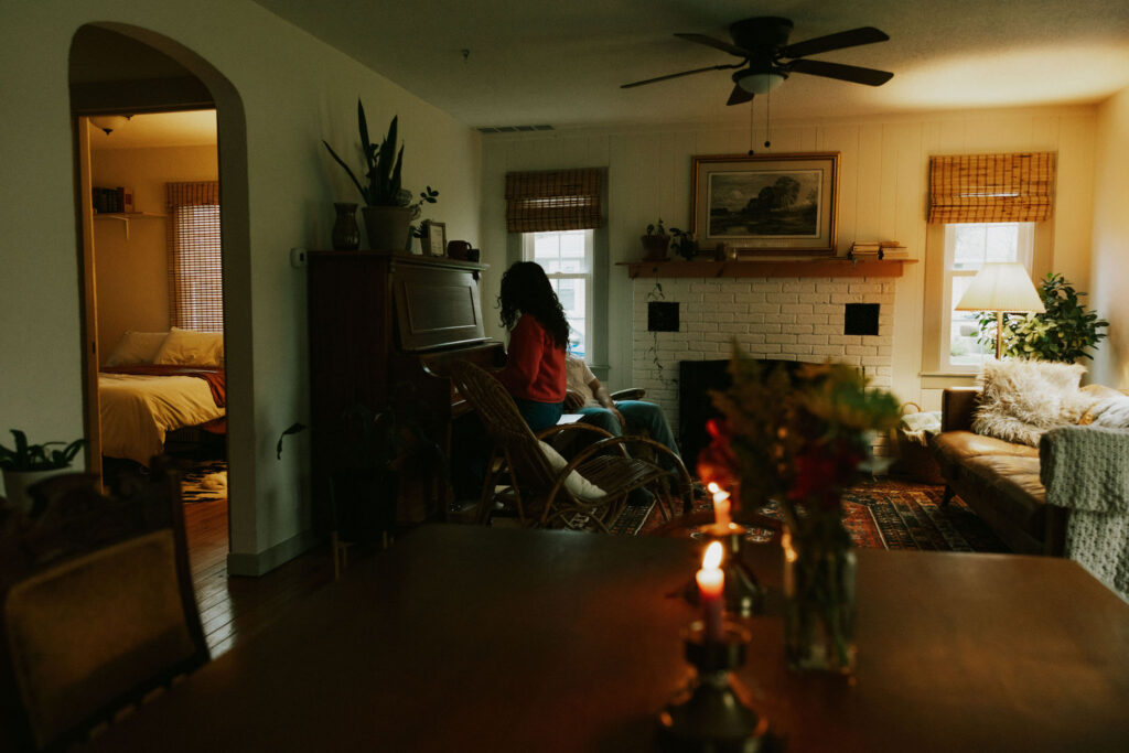 Couple cuddled in the living room at the piano of their home by candlelight.