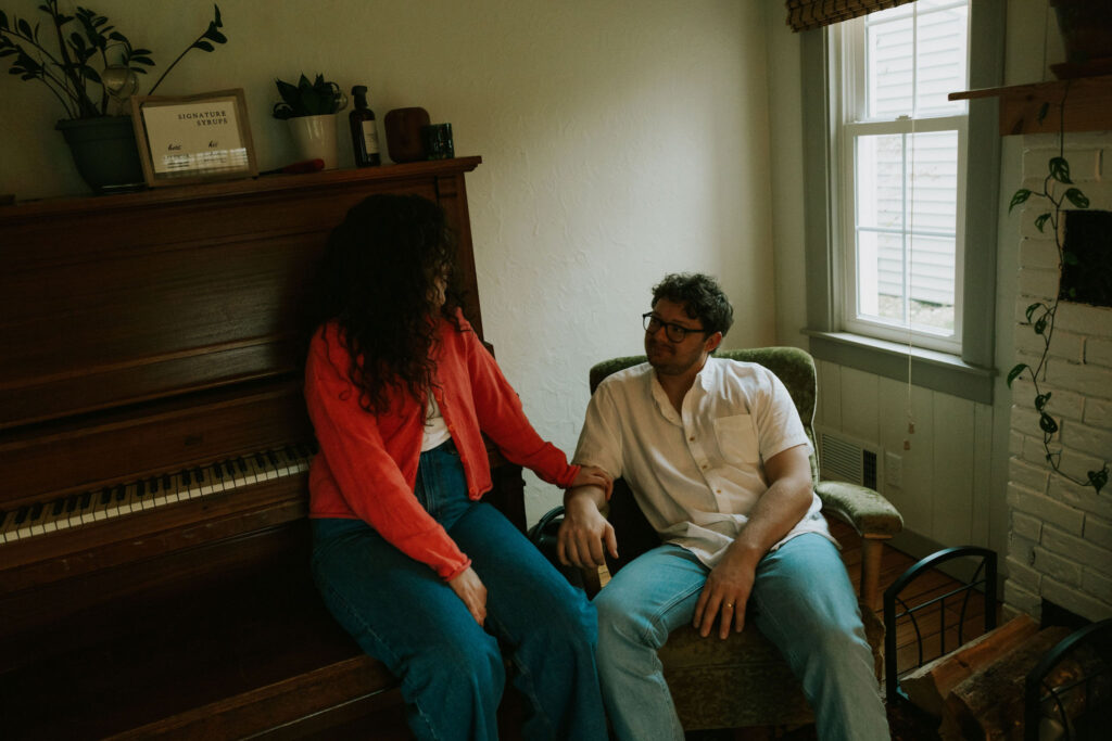 Couple cuddled in the living room at the piano of their home by candlelight.