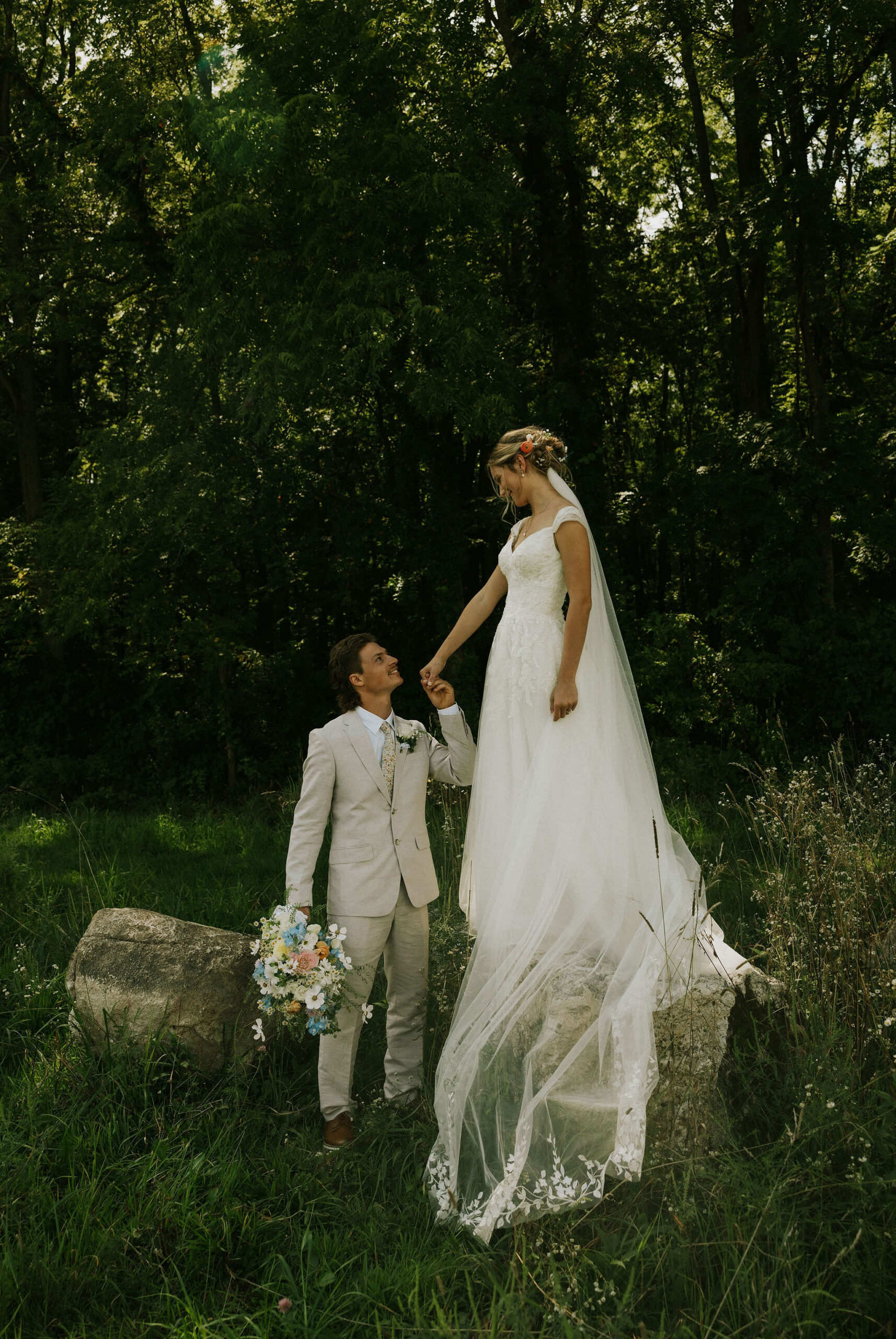 Bride and groom taking portraits together, groom kissing bride's hand.