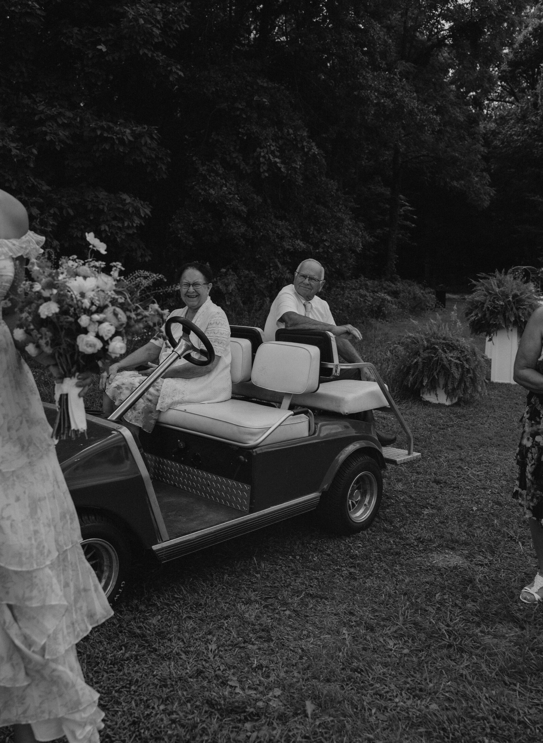 Bride's grandparents watch the bridesmaids take photos on their golf cart.