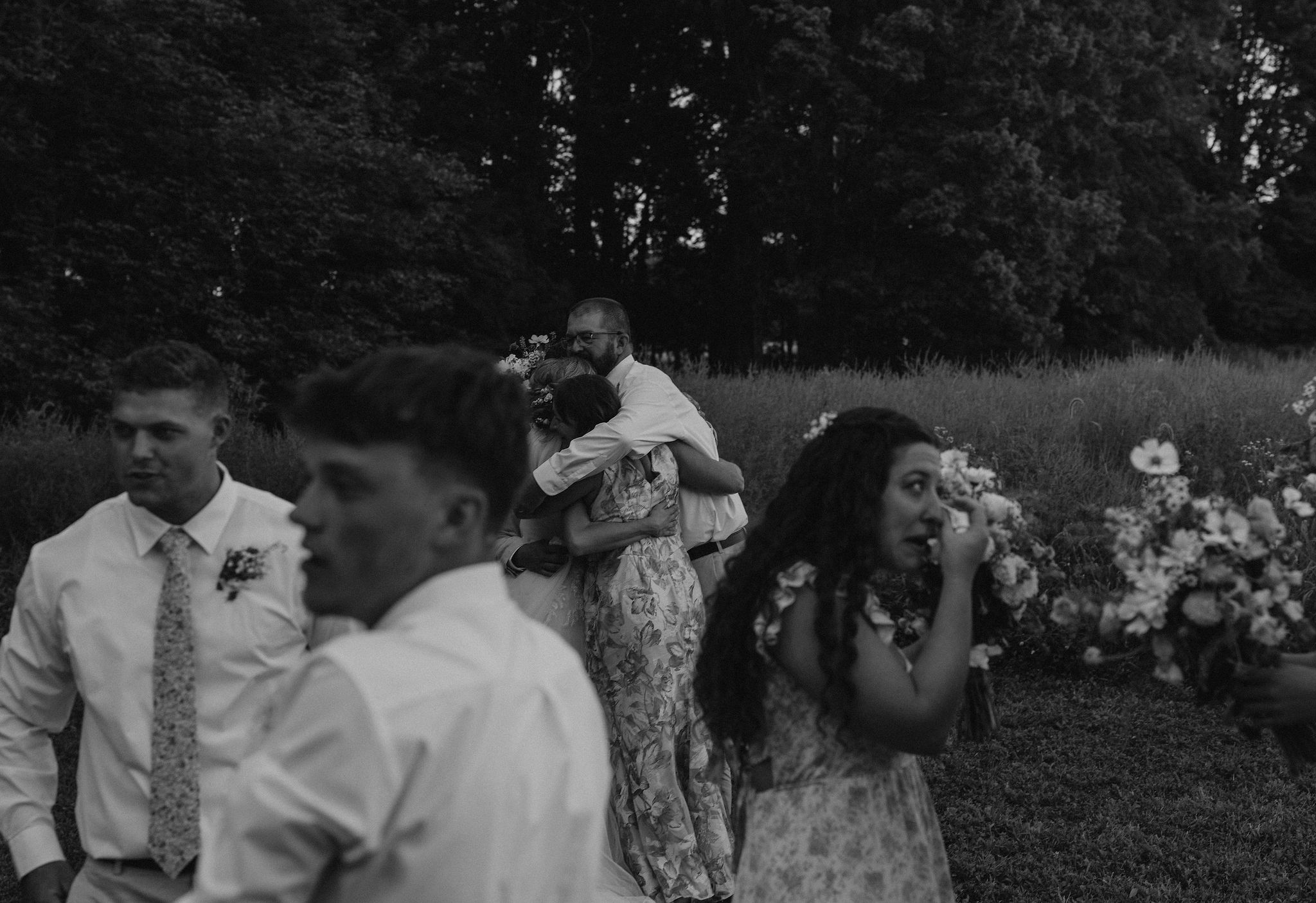 Bride and groom and family hug after the ceremony, and groom gets emotional.