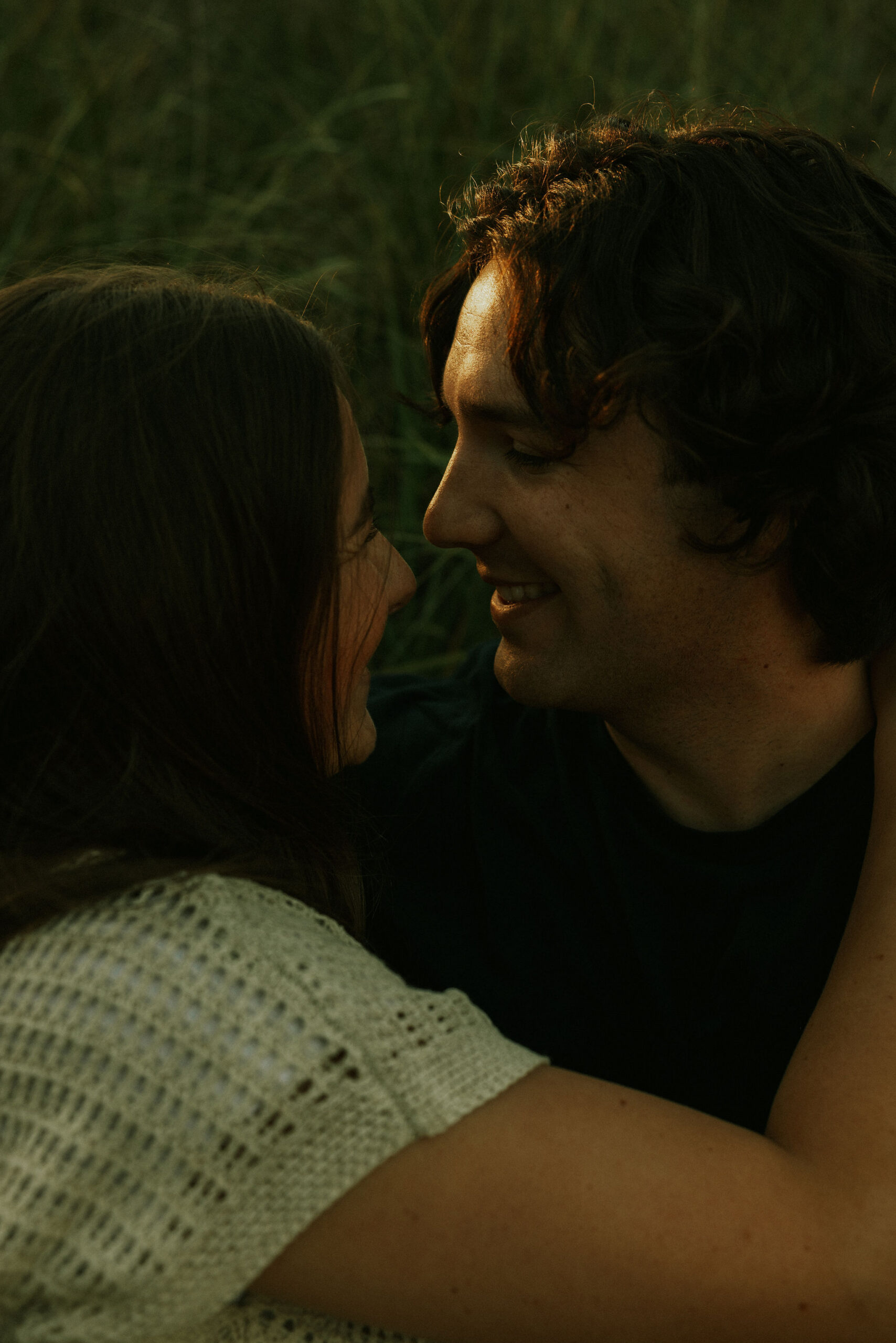 Engaged couple cuddled on the beach at Warren Dunes State Park.