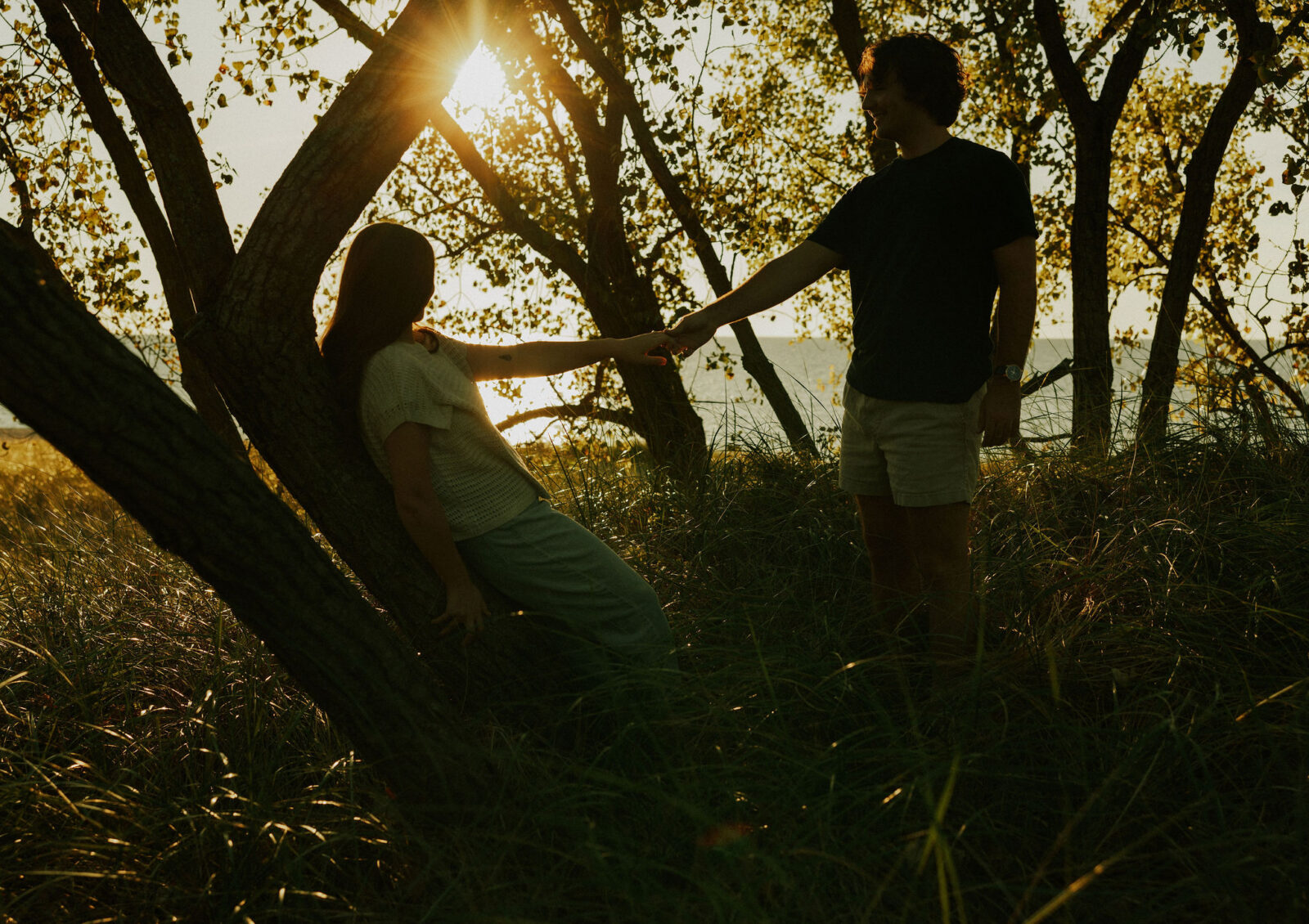 Engaged couple holding hands at Warren Dunes State Park.