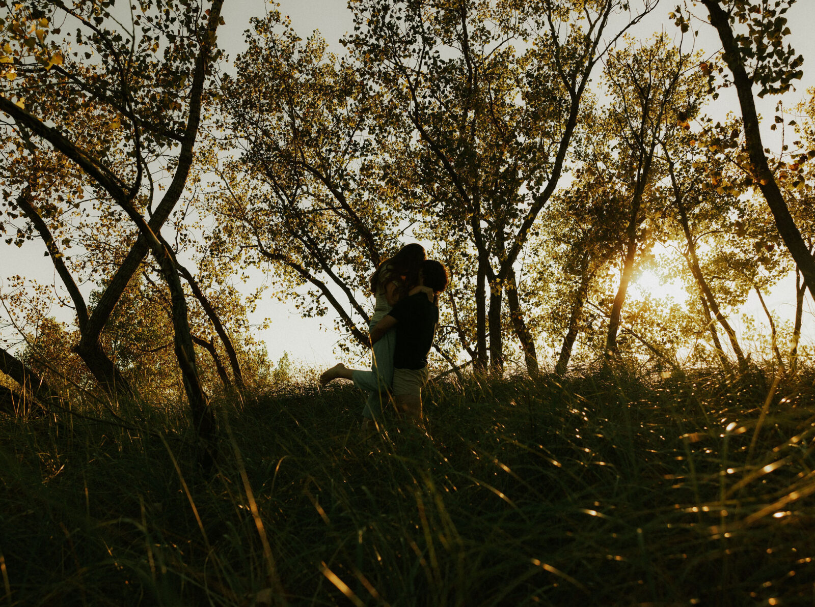 Couple hugging and twirling at the dunes in Warren Dunes State Park.