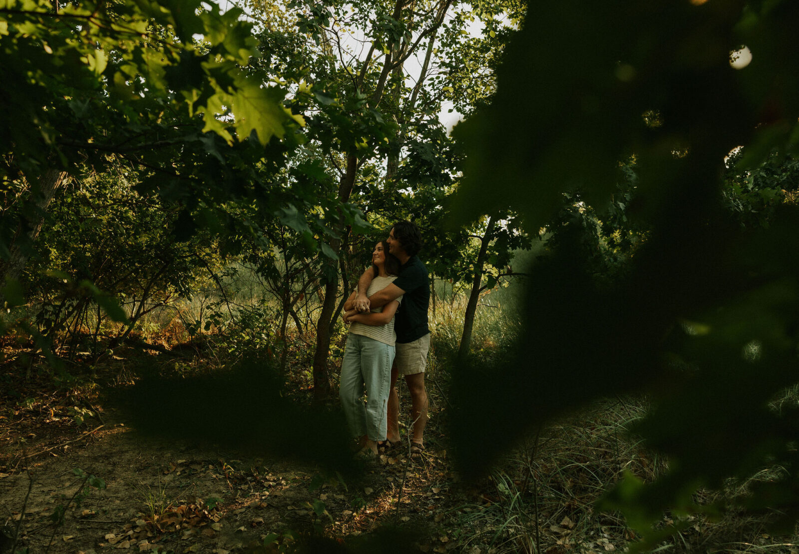 Engaged couple hugging in the forest at Warren Dunes State Park.