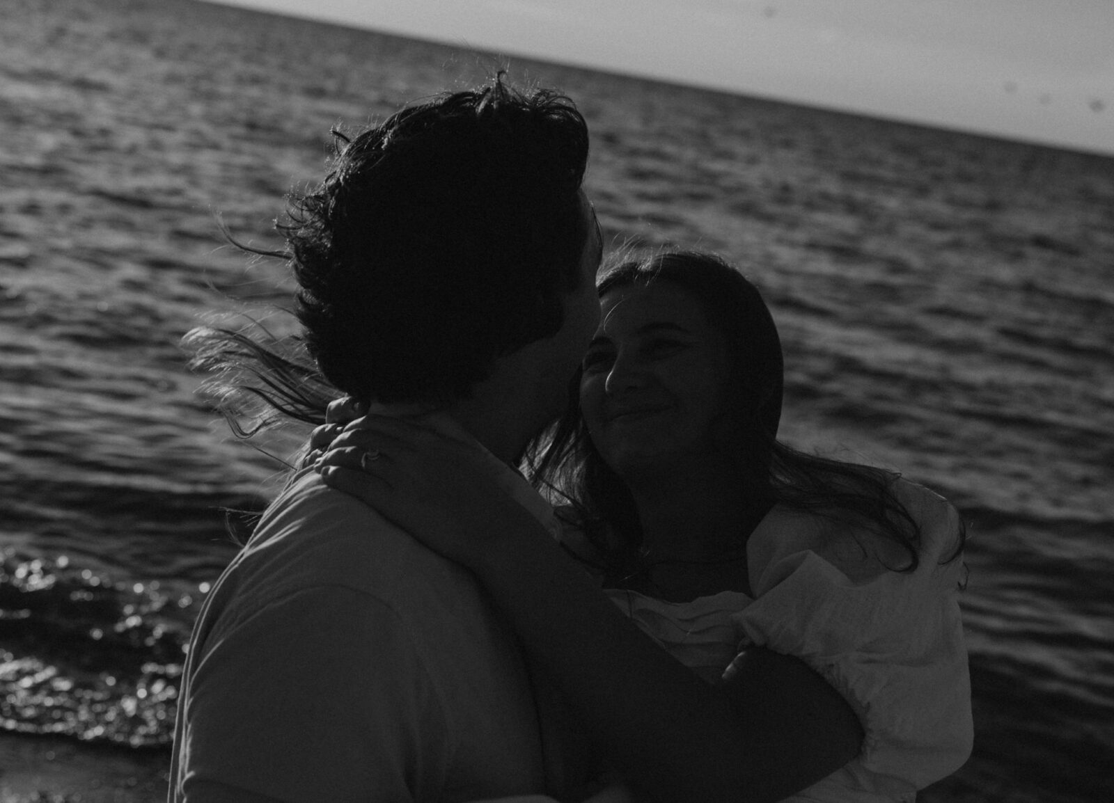 Groom picking up bride at engagement session on beach in Warren Dunes State Park.