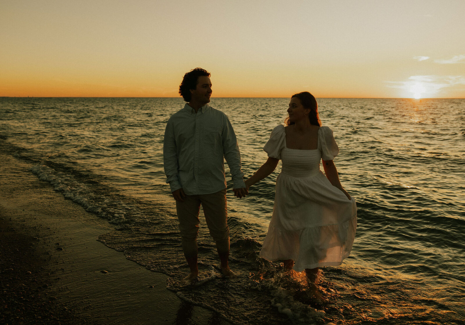 Engaged couple standing at water's edge at Warren Dunes State Park.