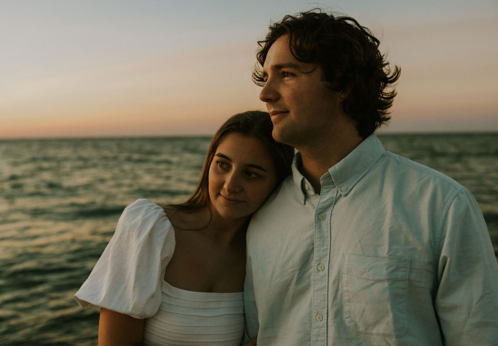 Engaged couple standing at water's edge at Warren Dunes State Park.