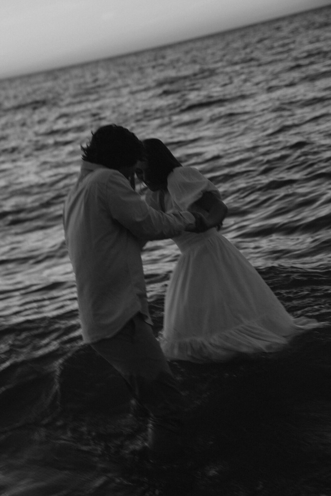Engaged couple spinning through the water together at Warren Dunes State Park.