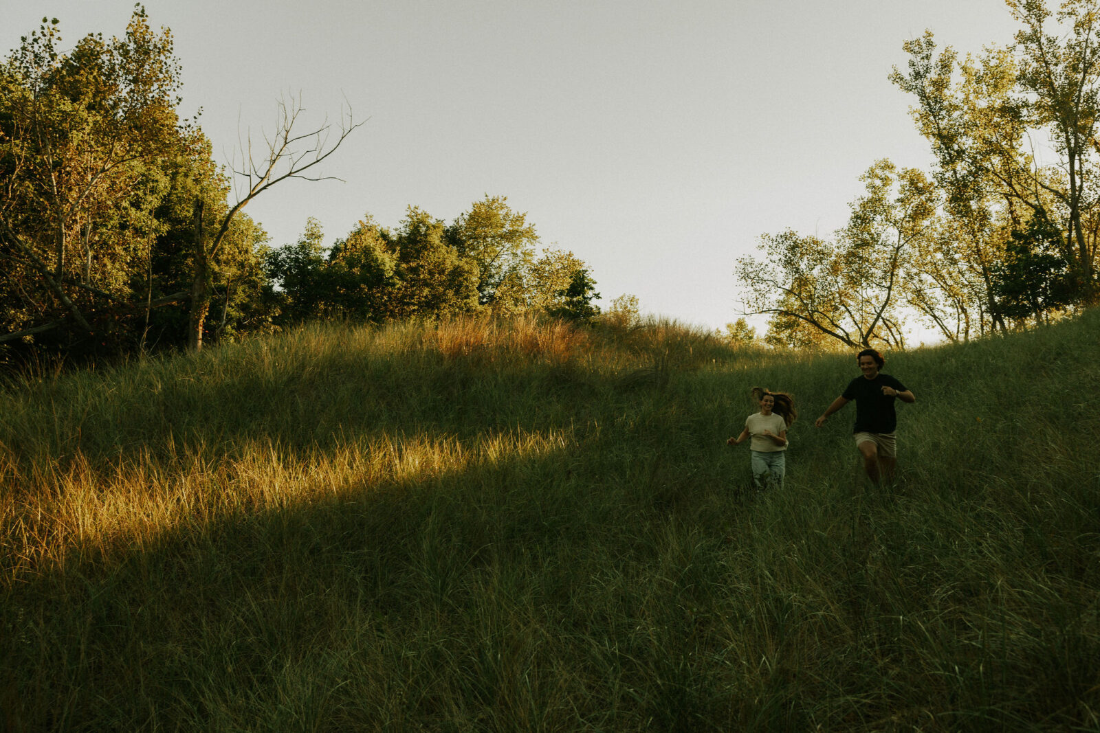Couple chasing each other through the dunes at Warren dunes state park.